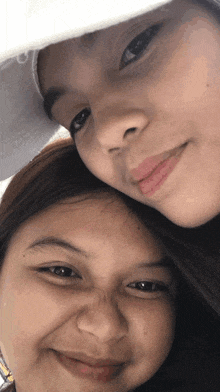 two girls are posing for a picture and one is wearing a hat