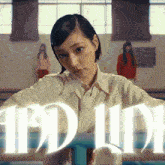 a girl in a white shirt stands in front of a sign that says " idol "