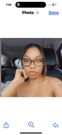 a woman wearing glasses is sitting in a car and the time is 7:40
