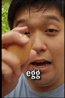 a man is holding an egg in front of his face and the word egg is on his face