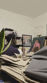a man in a purple shirt sits in front of a pile of cardboard boxes