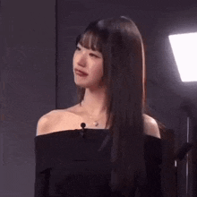 a close up of a woman wearing a black off the shoulder top and a microphone .