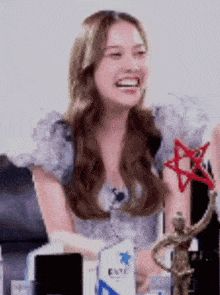 a woman is sitting at a table with a statue and a trophy and smiling .