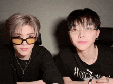 two young men wearing sunglasses and a shirt that says ' a ' on it are sitting next to each other