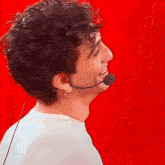 a man with curly hair is wearing a microphone around his neck and smiling .