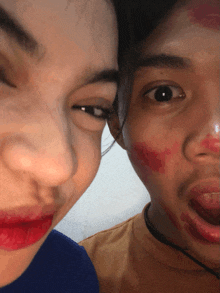 a man and a woman are posing for a picture and the woman has red lipstick on her face