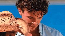 a man with curly hair wearing a straw hat