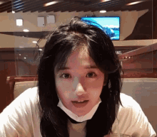 a woman wearing a mask looks at the camera in front of a screen that says channel