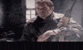 a man in a leather jacket holds a gun in his hand