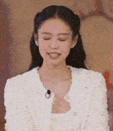 a close up of a woman wearing a white jacket with a microphone in her neck .