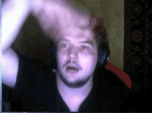 a man wearing headphones and a black shirt is looking at the camera