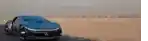 a blue car is driving down a dirt road .