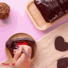 a person decorating a piece of chocolate cake with a red heart in the center