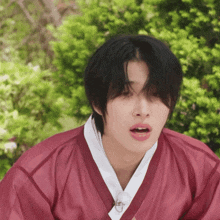 a young man wearing a red kimono with a white collar makes a funny face