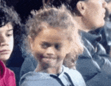 a little girl is smiling while sitting in a row with other children .