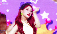 a woman with red hair is dancing in front of a purple background with stars