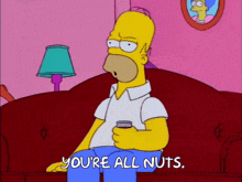 homer simpson is sitting on a couch holding a can of soda and saying " you 're all nuts "