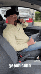 a man wearing a hat and glasses is talking on a cell phone in a car