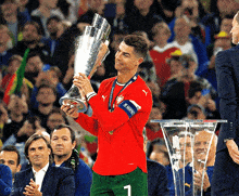 a soccer player holds up a trophy with the number 1 on his shirt