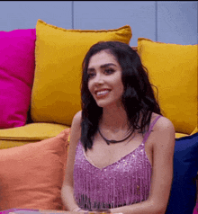 a woman in a purple top smiles while sitting on a couch