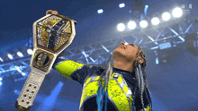 a woman in a yellow and blue outfit holds a championship belt