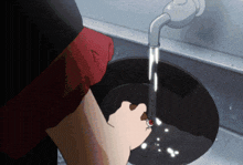a person is washing a frying pan under a faucet with water coming out of it