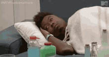 a man is laying on a bed with his head on a pillow next to bottles of soda .