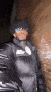 a man with curly hair is wearing sunglasses and a black jacket .
