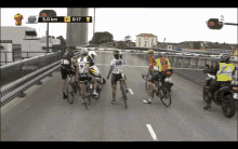 a group of people riding bikes on a bridge with the number 5 on the screen