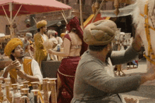 a man in a turban is talking to a woman in a red and gold outfit