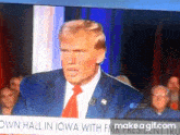a man in a suit and tie is giving a speech in front of a crowd in iowa ..