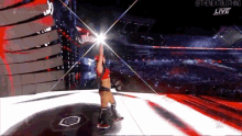a female wrestler is standing on a stage in front of a crowd with the words the nextbigthing live on the bottom left