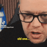 a man wearing glasses says " old one " in a video