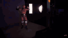 a man in a wrestling belt is standing in front of a light that says ' xpro ' on it