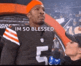 a man in a browns jersey is being interviewed by a woman in a crowd .