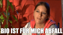 a woman is sitting in front of a plant with the words `` bio ist fur mich abfall '' written on the bottom .
