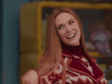 a woman is smiling and looking at the camera while wearing a red and white sweater .