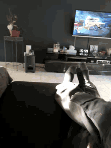 a person is sitting on a couch in front of a tv with a clock on the wall that reads 6:58