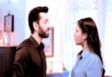 a man and a woman are looking at each other in a living room .
