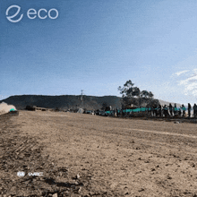 a group of people standing on the side of a dirt road with the word eco on the bottom right