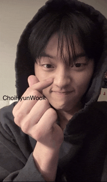 a young man wearing a hoodie is making a heart shape with his fingers