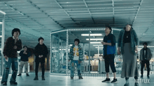 a group of people standing in a room with the word netflix on the bottom right
