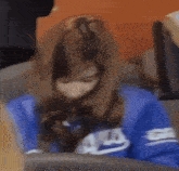 a woman wearing a blue nike sweatshirt is sitting on a chair