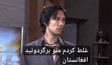 a man in a black shirt is standing in a room with a sign in a language other than english .
