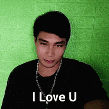 a man wearing a black shirt and a necklace is saying i love u .