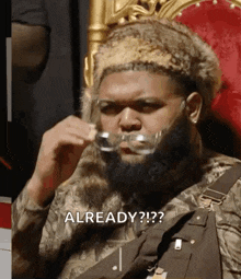 a man with a beard is sitting on a throne wearing glasses .