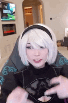 a woman in a white wig is sitting in a chair and talking to a man .