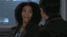 a woman with curly hair is talking to a man with her eyes closed