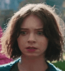 a close up of a woman 's face with short hair making a surprised face .