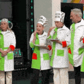 a group of chefs are standing next to each other on a stage eating food .